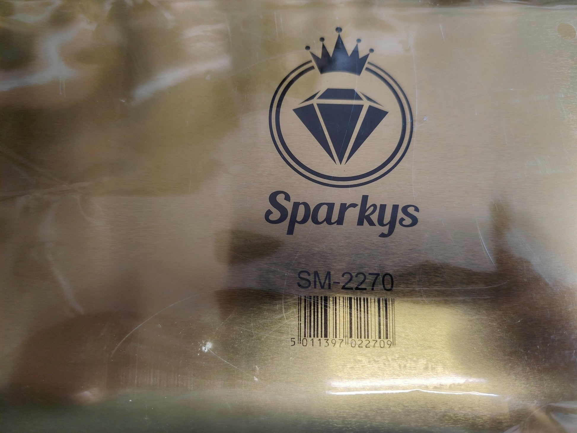 Plastic bag with 'Sparkys' branding and a barcode on a tray brass background
